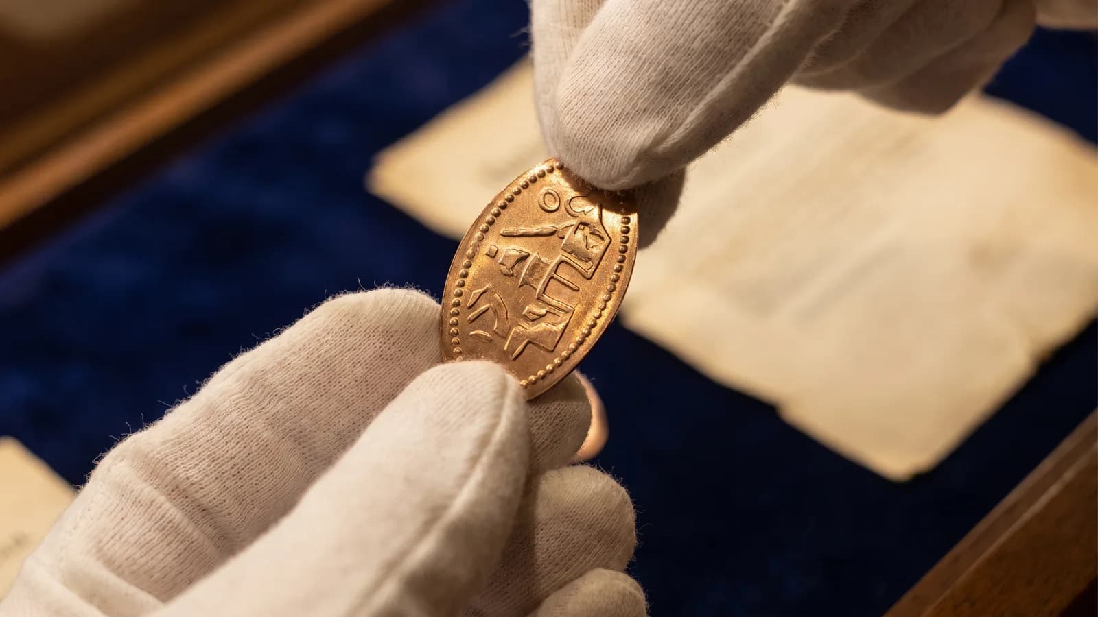 An oval pressed penny held between fingertips