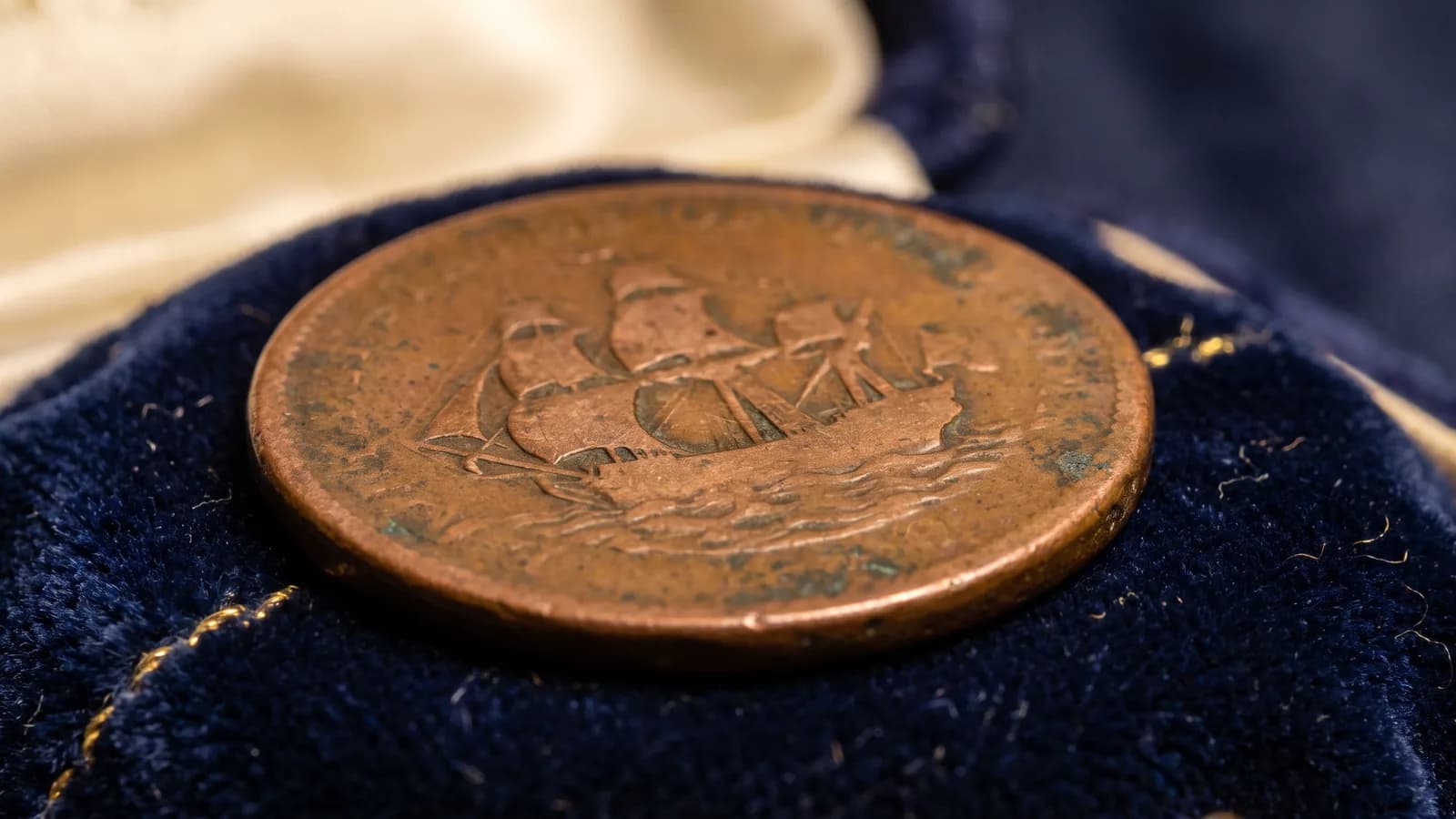 Macro of a faint sailing-ship relief on a copper token