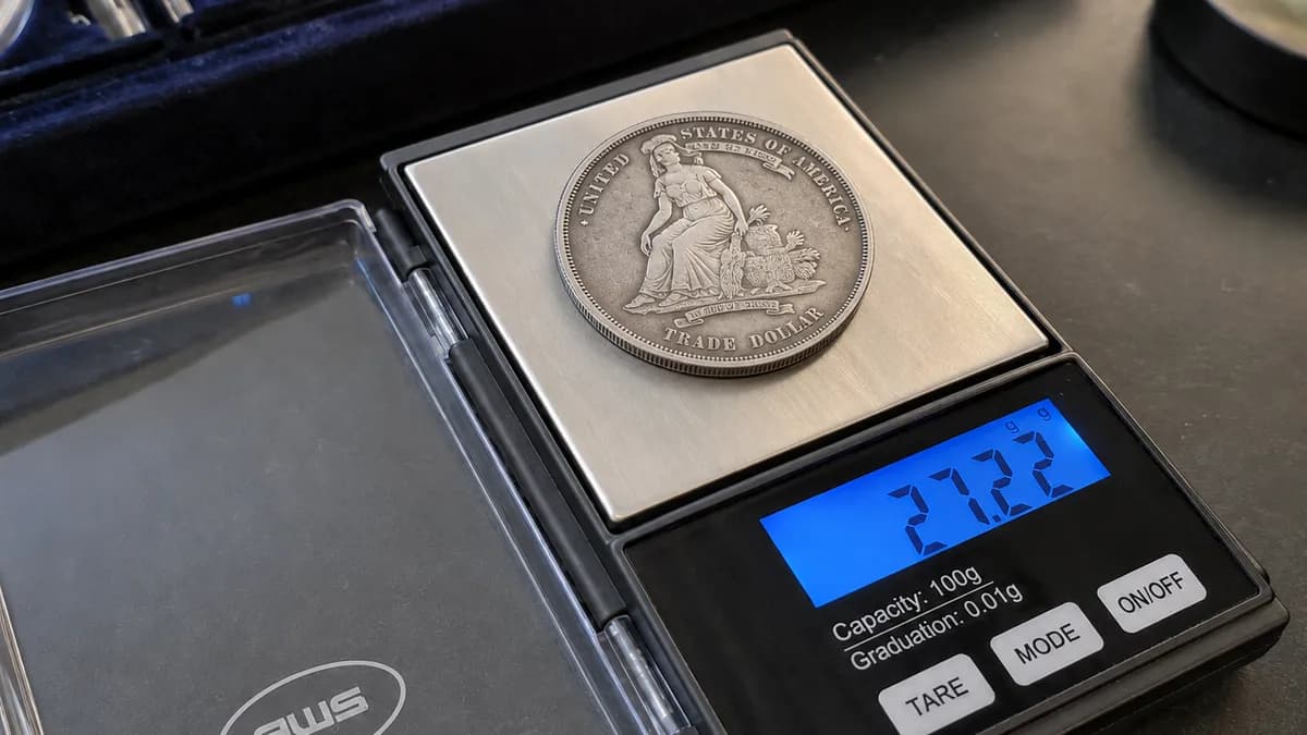 A coin dealer weighing a silver coin on a digital scale at the counter
