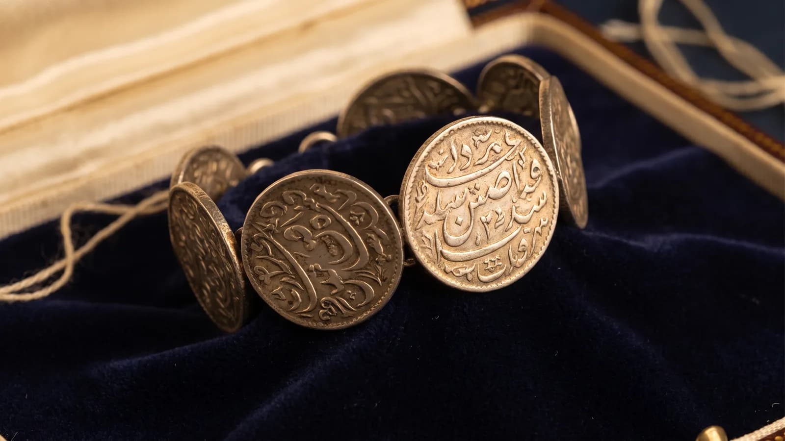 A bracelet of engraved love-token coins on velvet