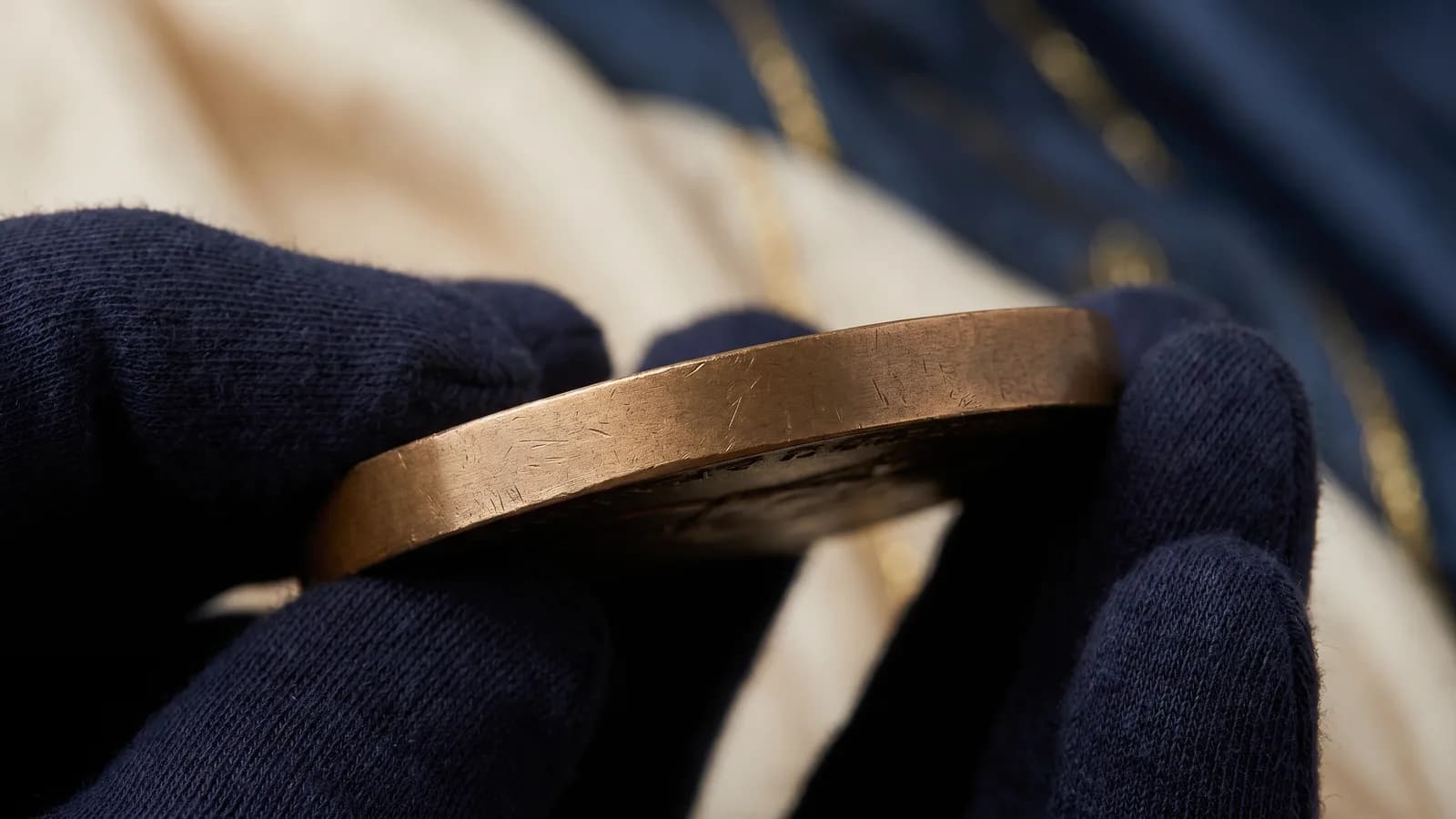 Macro of the plain edge of a bronze medal in gloved fingers