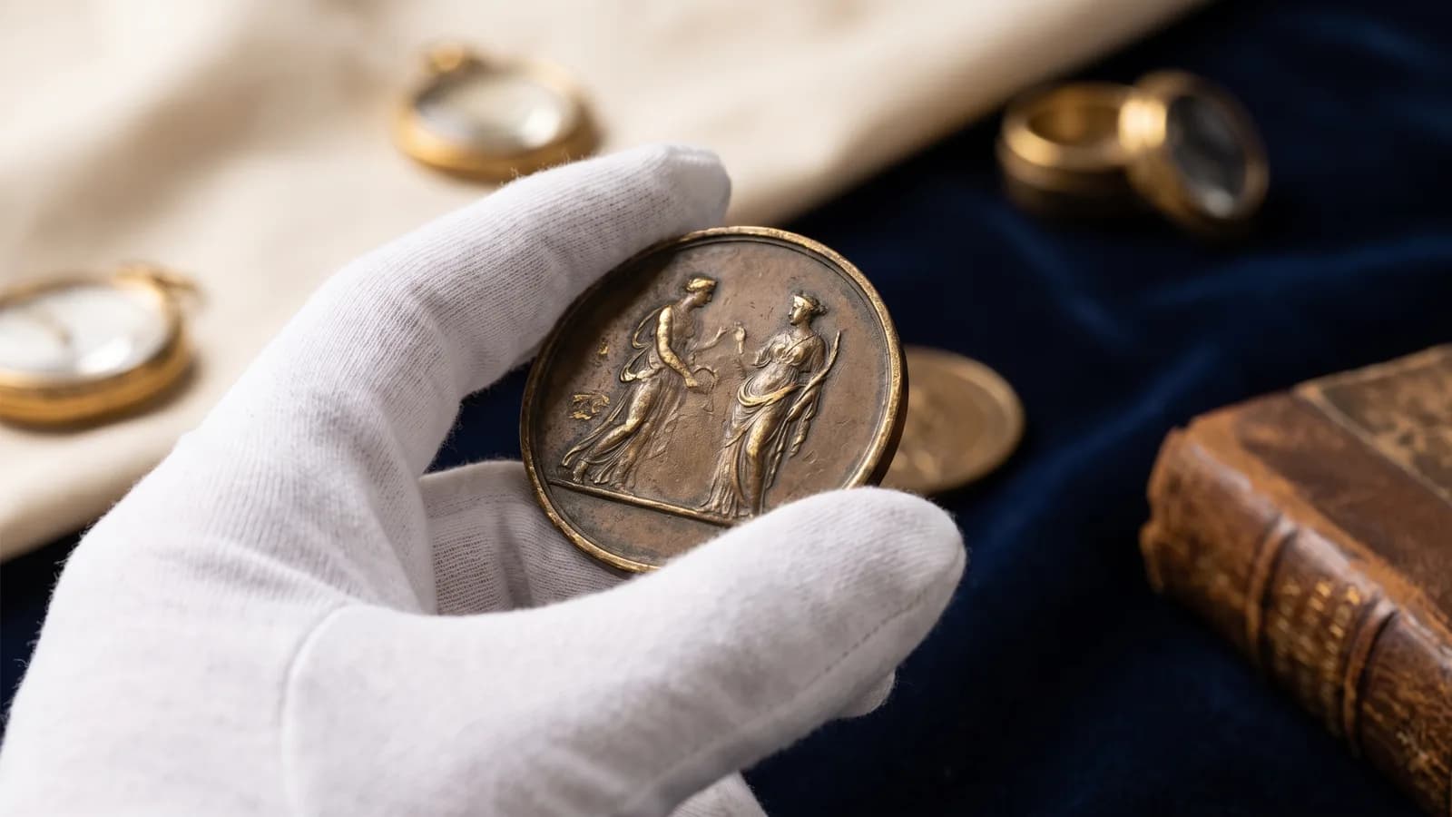 A gloved hand holding a dollar-sized medal to the light