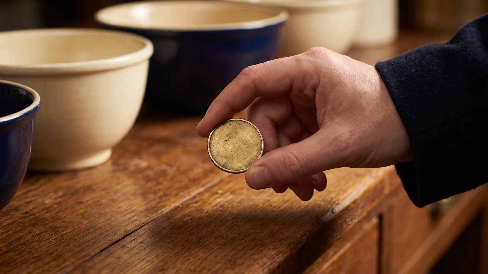 A single brass good-for trade token held in fingertips