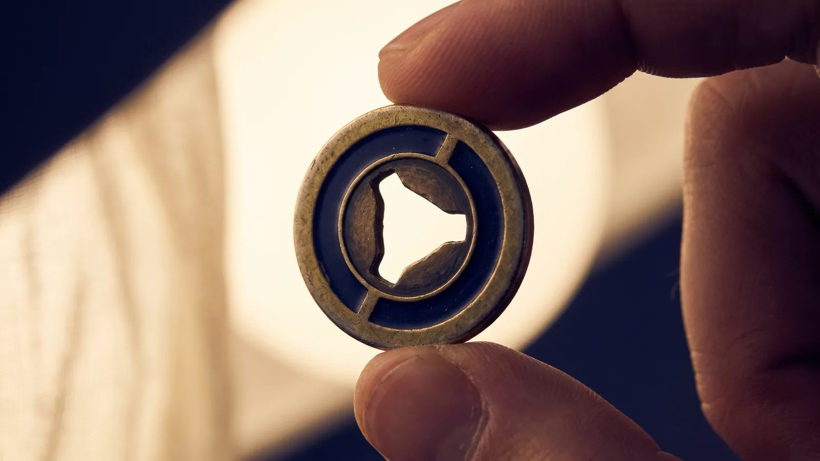 A transit token with a center cutout held to the light